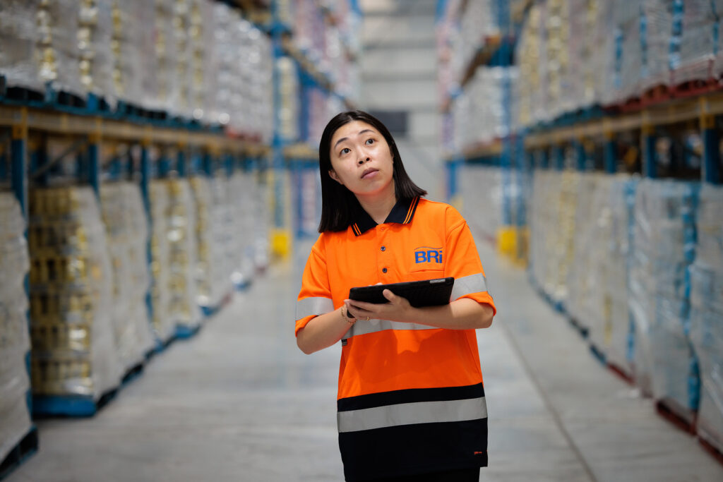 018 BRIFeb2024 4226 BRi warehouse worker in high-visibility vest using a handheld scanner to check stock among pallet racking